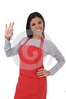 Corporate portrait of young attractive hispanic home cook woman in red apron posing happy and smiling isolated