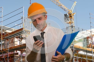 Corporate portrait of young attractive and successful engineer man or architect working on building at construction site wearing