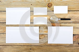 Business card. Corporate stationery set mockup. Blank textured brand ID elements on wooden table. Magnifier. Top view.