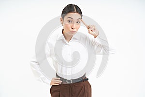 Corporate woman looks annoyed, points finger at head, mocks someone, scolding person, white background photo