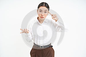 Corporate woman looks annoyed, points finger at head, mocks someone, scolding person, white background photo