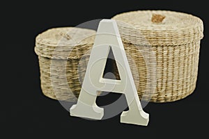 Corporeal Letter A uppercase white matte and wood with two wicker baskets on black background photo