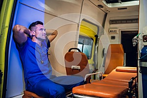 Corpsman in a blue uniform sitting in the ambulance car with his hands on the nape