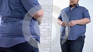 Corpulent man buttoning up tight shirt, oversize clothing problem, appearance
