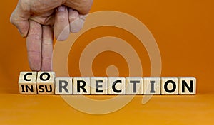 Businessman turns wooden cubes and changes word insurrection to correction. Beautiful orange photo