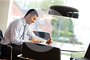 Correspondance made easy thanks to wireless technology. A young businessman using a digital tablet while sitting at a