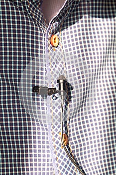 Correspondent attaches a lavalier microphone to a checked shirt