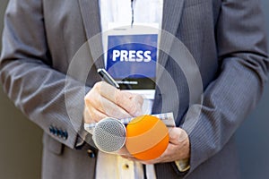 Correspondent or journalist at media event, holding microphone, writing notes. Journalism concept. photo