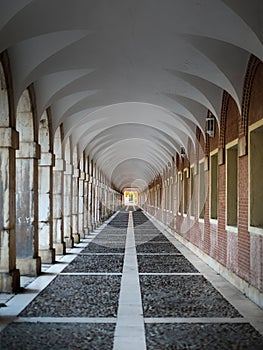 Corridor with columns and arches that form a tunnel. Casa de los Ninos in Aranjuez. Path around the sumptuous building, edited photo