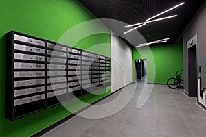 Corridor hall interior, with front door and elevator in many apartment building, with mailboxes with green walls