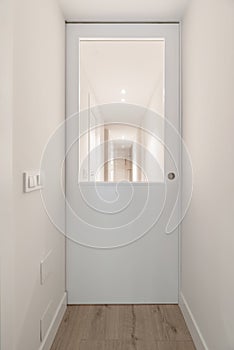 Corridor of a house with plain white painted walls, white lacquered doors with glass windows