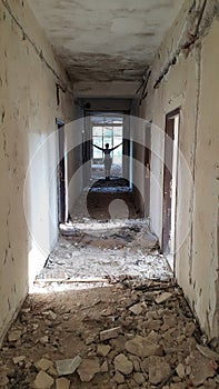 Corridor of ruined hotel with figure in the distance