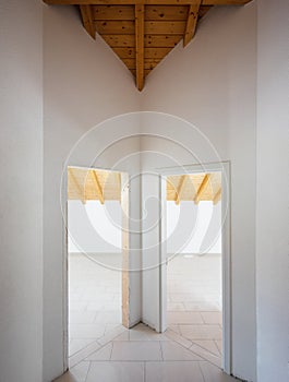 Corridor with two doors open on rooms with a sloping wooden roof