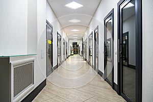 A corridor in an urban-type office building. Modern interior of the lobby of an office building with glass doors and clean white