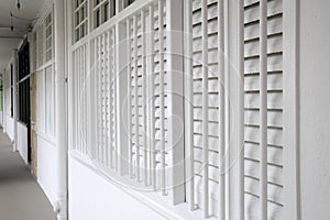 A corridor walkway with white painted housing apartment walls and wooden windows