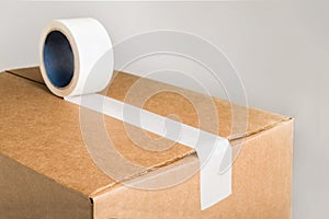 Corrugared brown cardboard box with white adhesive tape