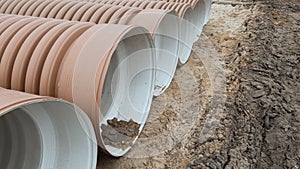 Corrugated Double-Walled Polypropylene Pipes Lined Up at a Construction Site During Daytime. Several large red