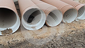 Corrugated Double-Walled Polypropylene Pipes Lined Up at a Construction Site During Daytime. Several large red