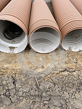 Corrugated Double-Walled Polypropylene Pipes Lined Up at a Construction Site During Daytime. Several large red