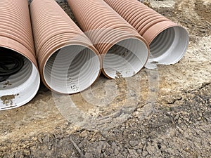 Corrugated Double-Walled Polypropylene Pipes Lined Up at a Construction Site During Daytime. Several large red