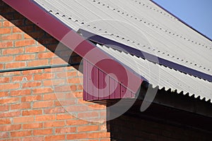 Corrugated metal profile of cherry color on the roof of the house