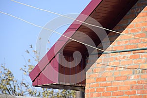 Corrugated metal profile of cherry color on the roof of the house