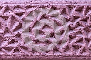 The corrugated surface of a plastered concrete wall covered with triangular depressions