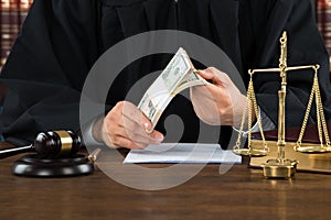 Corrupt Judge Holding Dollar Bundle At Desk