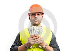 Corrupted builder man in handcuffs holding stolen money