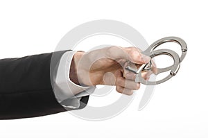 Corruption and bribery theme: businessman in a black suit with handcuffs on his hands on a white background in studio isolated