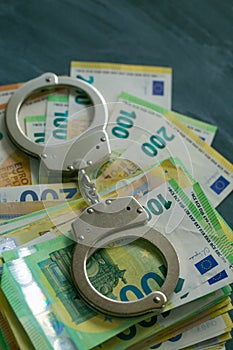 Corruption and waste of the budget in the European Union.Handcuffs, bills on chalkboard background.Taking bribes and