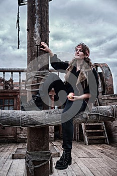 Corsair woman with an apple on board a wooden ship against a dark sky on Halloween