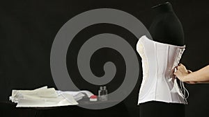 Corset lacing in the manufacturing plant underwear. Manufacture of underwear, tying lace corset seamstress. white corset