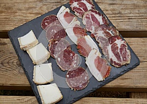 Corsican specialities, Coppa, Lonzo, salami sausage and goat cheese served on black stone plate.