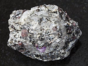 Corundum crystals in gneiss stone on dark