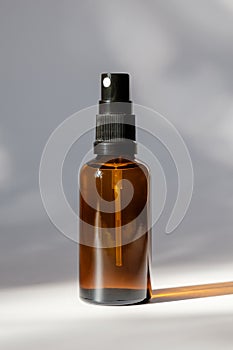Cosmetic amber glass bottle with sprayer on white background. Natural organic perfume packaging design photo