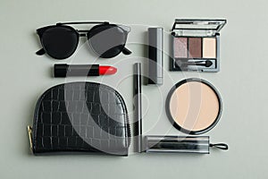 Cosmetic bag, makeup cosmetics and sunglasse on gray background photo