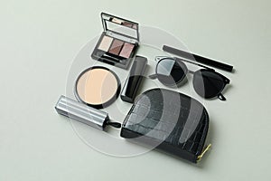 Cosmetic bag, makeup cosmetics and sunglasse on gray background photo