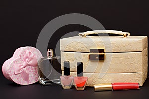 Cosmetic bag, perfume, nail polish and gift box on black background
