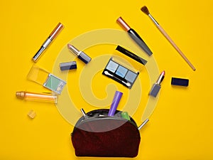 Cosmetic bag and women's cosmetics for make-up layout on a yellow background. Cosmetic shadows, make-up brush