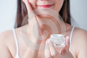 Cosmetic for beauty skincare, facial treatment concept. woman apply moisturizer lotion on her face from luxury white cosmetic