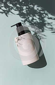 Cosmetic body lotion bottle on the noon sunlight with leaves shadow.
