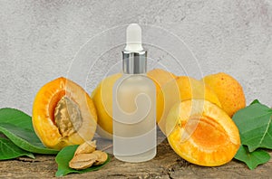 Cosmetic bottle with apricot essential oil and fresh apricot fruit on a wooden table. Essential oil of apricot