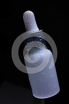 Cosmetic bottle with an eyedropper on a black background close-up