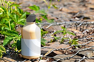 Cosmetic bottle in green leaves on stones with wire