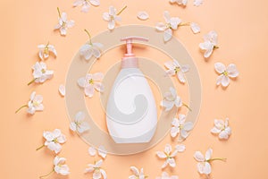 Cosmetic bottle of liquid soap cream for moisturizing and caring for body and face against a background of fresh flowers