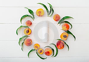 Cosmetic bottle, peach cosmetics toiletries in Peaches frame. Peaches, leaves on white wooden background with peach in halves.