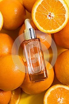 Cosmetic bottle product serum vitamin C with orange and lemon flat lay on yellow background, top view, copy space