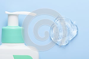 Cosmetic bottle with pump dispenser and transparent gel smear on blue background