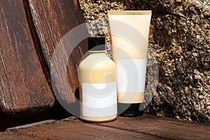 Cosmetic bottle and tube on wood and stone background